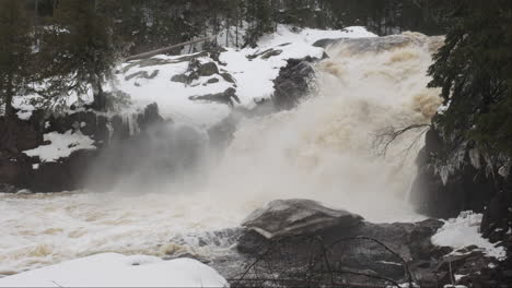 Minnesota-waterfall-roars,-its-cascading-waters-swollen-with-the-surge-of-spring's-melting-snow