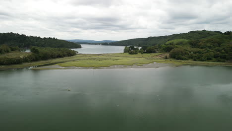 Dolly-Downward-Aerial-of-A-Large-Twisting-River-Lush-Green-Trees-with-Canoe