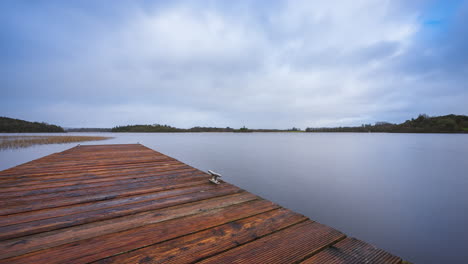 Zeitraffer-Eines-Hölzernen-Seestegs-Im-Vordergrund-Und-Einer-Burgruineninsel-Mit-Wald-In-Der-Ferne-An-Einem-Bewölkten-Sonnigen-Tag-Am-Lough-Key-In-Der-Grafschaft-Roscommon-In-Irland