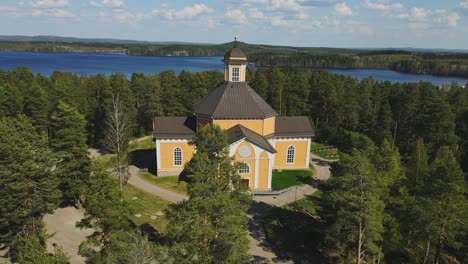 Kirche-Von-Laukaa,-Finnland,-Dolly-In-Drohnenaufnahme-Der-Alten-Holzkirche-Inmitten-Von-Seen-Und-Wäldern-An-Einem-Schönen-Sommertag