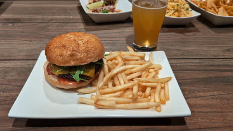 Close-up-of-Burger-and-fries-with-a-beer-on-a-wooden-table