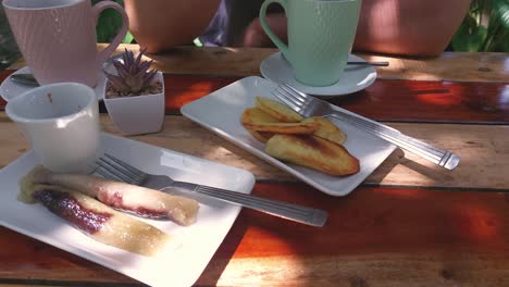 Overhead-view-of-a-traditional-Filipino-merienda-of-suman-and-fried-kamote-served-with-coffee-with-partial-view-of-a-person-eating