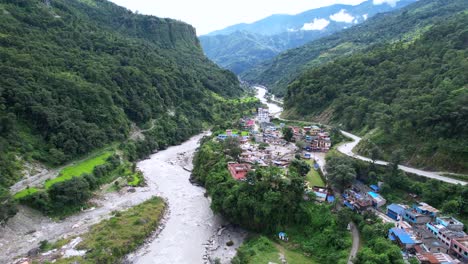 Exotic-aerial-rural-scene-of-Gandaki-River-and-green-trees-on-the-mountainside,-drone-flying-forward-above-Marpha-Village-in-Nepal