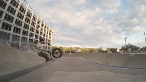 BMX-bike-rider-does-huge-tweaked-air-over-skatepark-bowl-spine-gap-in-extreme-800fps-slow-motion,-4k-fisheye-push-in-bike-trick-at-sunrise