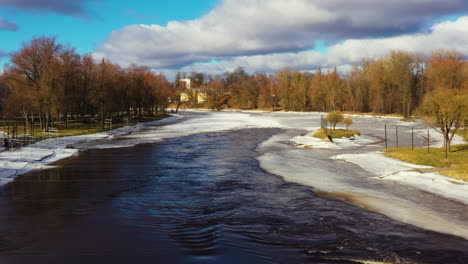 Canoe-track-gates-in-quick-flowing-icy-Gauja-river,-Valmiera-Latvia,-aerial-dolly
