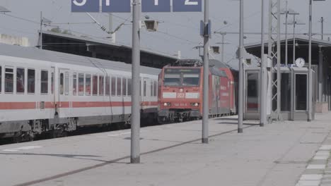 Red-Deutsche-Bahn-train-arriving-at-a-station-during-the-day,-clear-weather