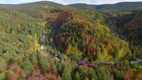 Aerial-establishing-shot-of-the-beautiful-village-hidden-in-the-mountain-forest-in-autumn