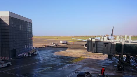 Air-Canada-aircraft-arriving-at-airport-terminal-gate-with-loading-bridge-and-operators-ready-for-ground-operations,-Rome-Fiumicino-in-Italy