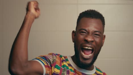 Retrato-De-Un-Hombre-Afroamericano-Con-Camisa-De-Tela-Kente-Celebrando-Emocionantemente-En-Cámara-Lenta