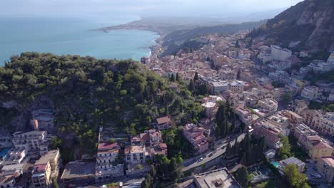 Aerial-dolly-shot-of-Taormina,-Sicily,-Italy-a-famous-tourist-destination-surrounded-by-the-emerald-waters