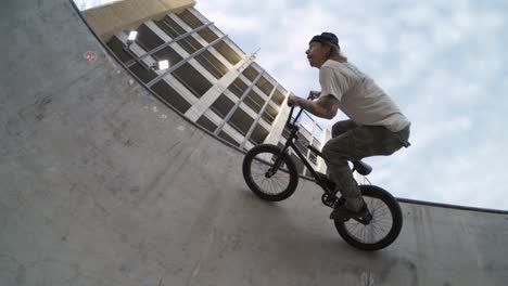 Ciclista-Bmx-Montando-De-Lado-A-Lo-Largo-De-La-Parte-Superior-Del-Skatepark-En-Cámara-Lenta-Extrema-De-800-Fps,-Toma-De-Seguimiento-Con-Lente-Ojo-De-Pez-Al-Amanecer