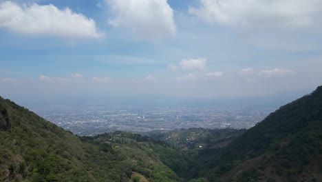 Drohnen-Dolly-Aufnahme,-Die-Aus-Der-Sicht-Von-San-Jose-Costa-Rica-Zwischen-Bergen-Wegzieht