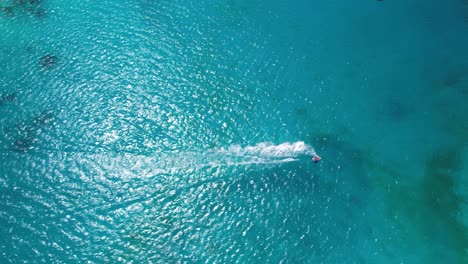 Speedboat-cutting-through-turquoise-waters,-top-down-aerial-view,-sunny-day