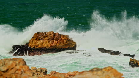 Aquamarine-ocean-waves-surges-over-rock-creating-frothing-whitewash,-telephoto