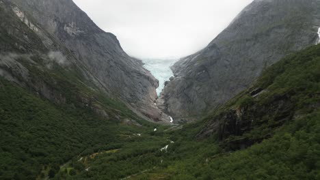 large-glacier-in-a-green-valley,-big-forrest-with-mountains,-Briksdalsbreen,-norway,-nature,-drone