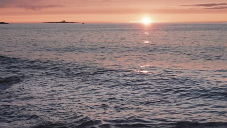 Olas-Iluminadas-Por-El-Cálido-Resplandor-Del-Sol-Poniente-Que-Avanzan-Lentamente-Hacia-La-Costa-Rocosa.