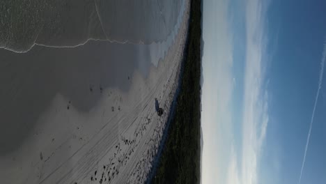 Vertical-drone-shot-of-car-on-sandy-beach-of-Wylie-Bay-during-sunny-day