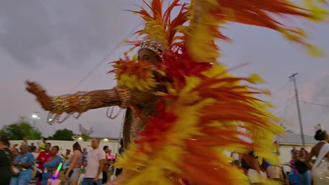 Carnival-king-dances-and-shakes-body-with-golden-sparkle-paint-and-orange-red-feathered-costume