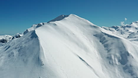 Heller,-Schneebedeckter-Berggipfel-Unter-Einem-Klaren,-Blauen-Himmel,-Klar-Und-Heiter-Am-Helllichten-Tag,-Luftaufnahme