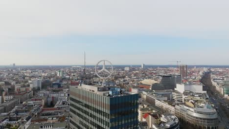 Spinning-around-Mercedes-Benz-logo-on-rooftop-of-headquarters-building-on-sunny-day---aerial-drone-view