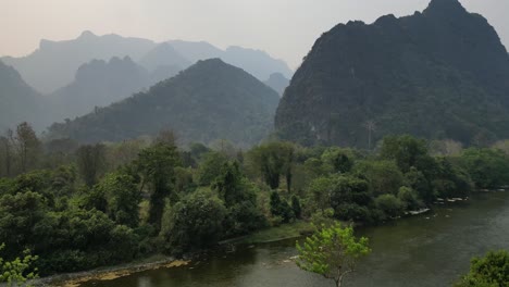 Volando-El-Dron-Sobre-Los-árboles-En-Laos,-Capturando-Una-Increíble-Vista-Aérea-De-Las-Montañas-Que-Se-Encuentran-Más-Adelante