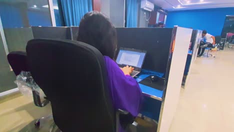 In-a-quick-look-at-the-call-center,-we-see-an-employee-in-a-purple-outfit,-diligently-typing-on-her-laptop,-completely-engrossed-in-her-tasks