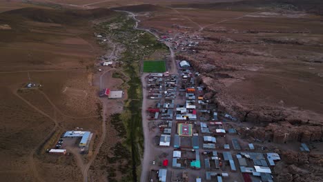 Un-Pequeño-Y-Colorido-Pueblo-Enclavado-En-El-Vasto-Y-árido-Paisaje-De-Chile-Al-Atardecer,-Vista-Aérea