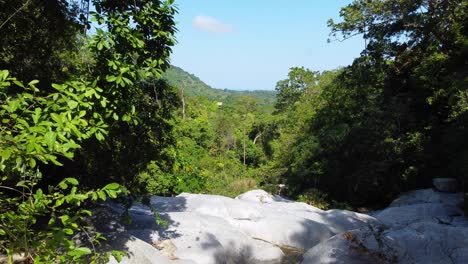 Fly-through-drone-shot-of-the-dry-riverbed-that-flows-through-a-lush-rainforest-located-in-Santa-Marta,-Colombia-in-South-America