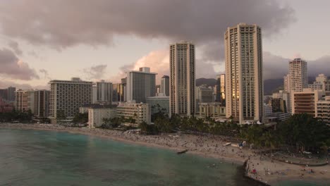 Beachfront-Hotel-Buildings-on-Waikiki-Coastline-at-Sunset,-Hawaii,-Aerial