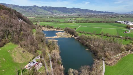 Oberriet-In-Der-Schweiz-Mit-Einem-Mäandernden-Fluss,-üppigen-Feldern-Und-Fernen-Hügeln,-Unter-Einem-Klaren-Himmel,-Luftaufnahme