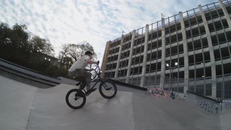 Biker-360-spins-in-slow-motion-at-skatepark,-beanie-flies-off,-4k-800fps-bmx-trick-at-sunrise