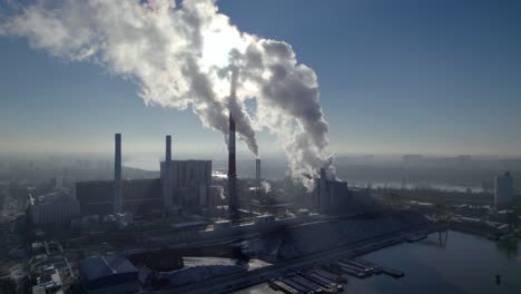 Aerial-descend-shot-of-a-coal-fired-heating-power-station-with-thick-white-smoke-coming-from-the-chimney,-environmental-pollution-concept