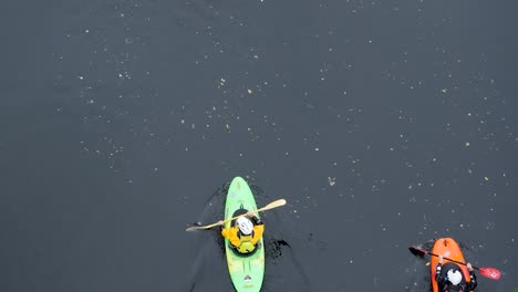 3-Coloridos-Kayaks-En-Un-Río-Sombrío-Remando-En-Una-Aventura-Acuática