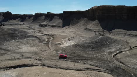 Drohnenaufnahme-Eines-Roten-Geländewagens,-Der-Sich-In-Der-Trockenen-Wüstenlandschaft-Von-Utah,-USA,-Bewegt