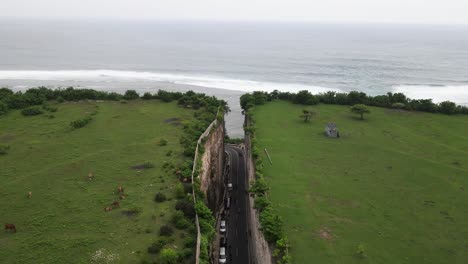 Aerial-view,-asphalt-road-that-penetrates-the-cliffs-of-Tanah-Barak-on-the-island-of-Bali-to-connect-to-Pandawa-beach