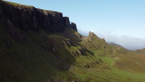 Aerial-drone-fly-above-green-panoramic-cliffs-trekking-at-The-Quiraing,-Isle-of-Skye,-Scotland-skyline-at-summer,-slow-motion-establishing-shot-above-mountain-formation