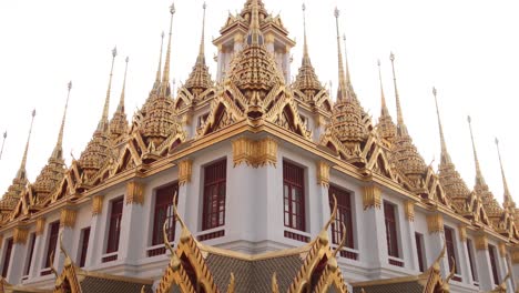 looking-up-at-towering-detailed-golden-pagoda-spires-in-a-buddhist-temple-complex-in-the-Rattanakosin-old-town-of-Bangkok,-Thailand