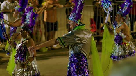 Old-man-parties-in-shiny-costume-with-beautiful-woman-in-carnival-parade-at-night