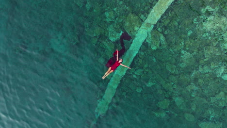 Vista-De-Arriba-Hacia-Abajo-De-Una-Mujer-Vestida-De-Rojo-Nadando-En-El-Mar-Adriático-En-Croacia---Disparo-De-Un-Dron