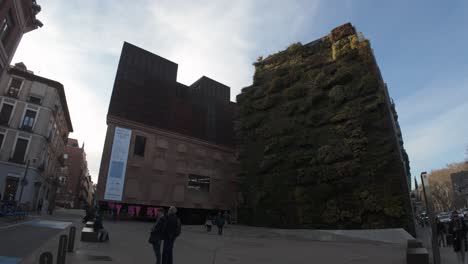 establishing-shot-of-caixa-forum-museum-in-Madrid,-Spain-with-vertical-garden-facade-and-industrial-brick-on-a-sunny-winter-day