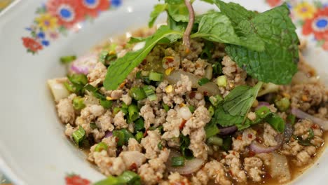 Close-up-of-a-plateful-of-a-popular-Isan-Thai-food-called-Larb,-a-mixture-of-minced-chicken,-mint,-chili-pepper,-coriander,-lime,-and-fish-sauce