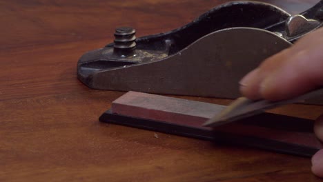 Blade-from-antique-vintage-wood-plane-is-sharpened-on-a-whetstone