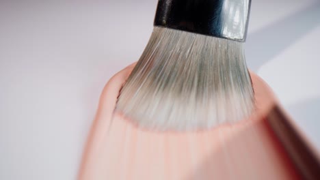 A-brush-that-spreads-base-make-up-in-fluid-on-white-surface