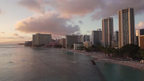 Aerial-Of-Waikiki-Beach-At-Sunset-In-Hawaii,-People-Swimming-And-Surfing
