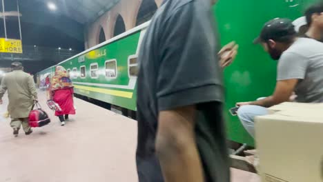 Green-train-arrives-at-Lahore-station-and-people-wait-to-board