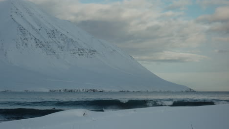 Slow-motion-tracking-follows-surfer-catching-wave-and-riding-down-face-at-base-of-snowy-mountain