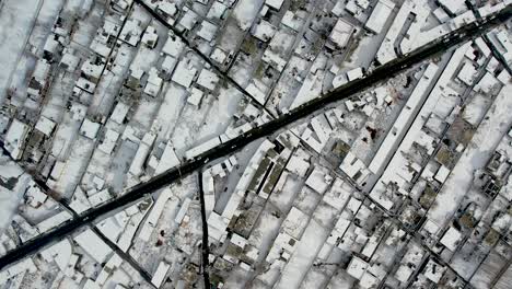 Drone-shot-of-the-city-of-Skardu-from-above,-snow-covered-and-a-road-with-cars