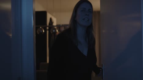 Worried-woman-opening-hallway-door-at-night-and-call-out