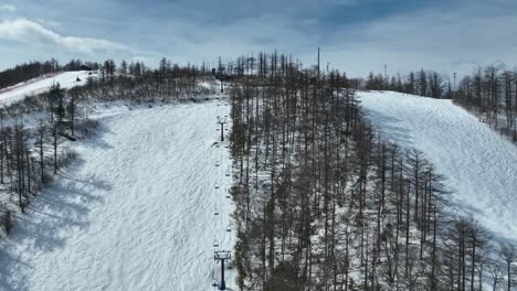 Aufsteigende-Drohnenaufnahme,-Die-Den-Berg-Hinauffliegt-Und-Dem-Sessellift-Zum-Gipfel-Des-Schneebedeckten-Skibergs-Folgt