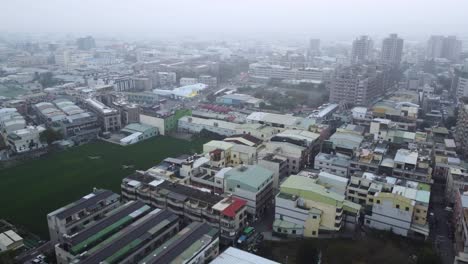 Overcast-cityscape-with-dense-buildings,-aerial-view-of-an-urban-area-on-a-cloudy-day